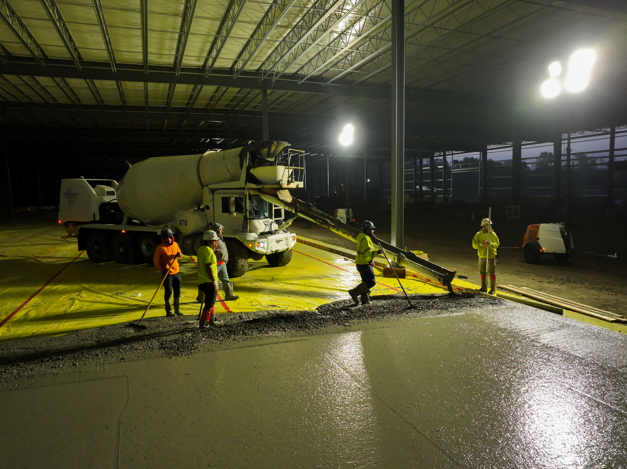 Night photo of concrete pour at a large construction site with workers and cement truck