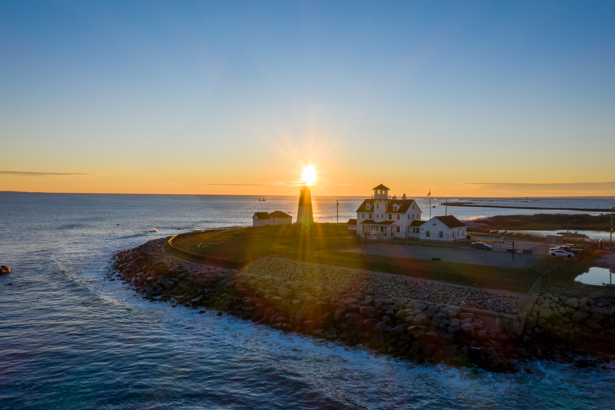 Drone photo of a Rhode Island lighthouse at sunrise with ocean waves