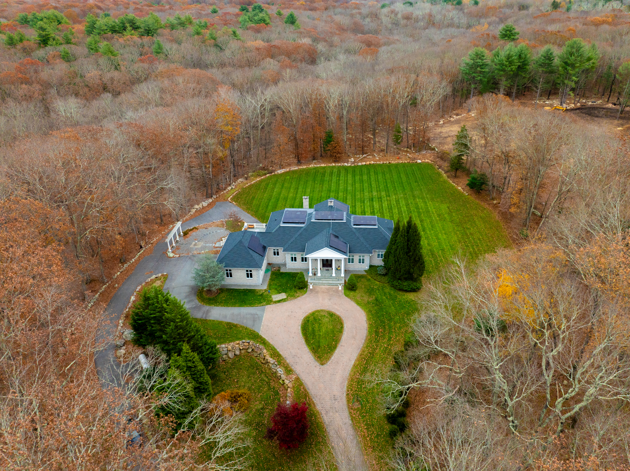 Drone photo of a large estate surrounded by autumn woodland with circular driveway
