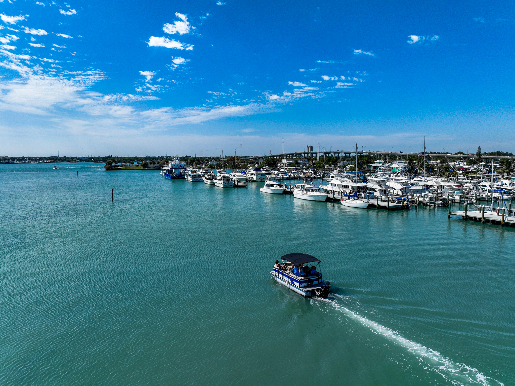 Drone shot of a marina with boats and a pontoon boat on turquoise water
